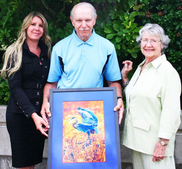 Whidbey Telecom’s Julia DeMartini and Marion Henny flank cover art competition winner Dan Karvasek who holds his winning photograph.