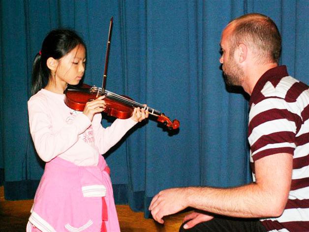 Violinist teo Benson teaches on of the students in Seattle.