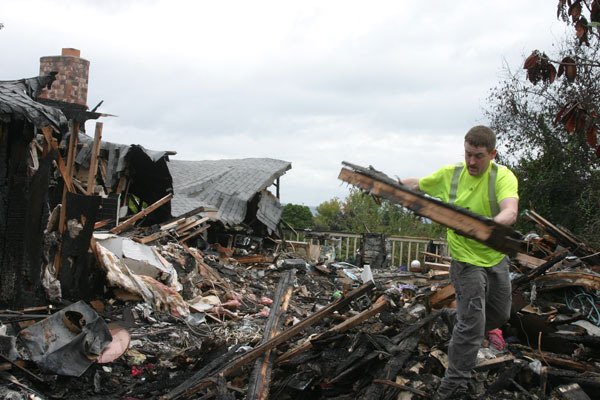 Ben Watanabe / The Record Dustin Haul wrenches a charred and broken beam from the debris pile at the ruin of 460 Anthes Avenue on Tuesday. He was there with Thermatech Northwest