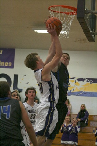 Falcon senior Nick Bennett challenges Friday Harbor’s Gabe Lawson at the rim on Saturday. Friday Harbor won the game on its home court 55-45 to keep the Falcon boys winless early in the boys basketball season.