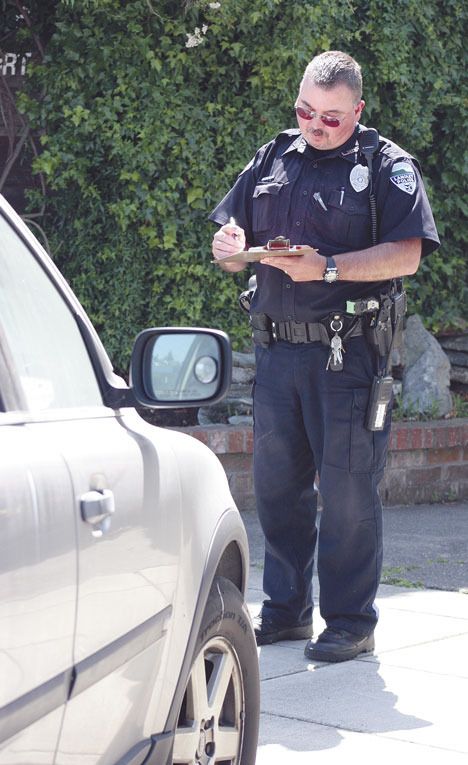 Langley Police Officer Randy Heston writes a warning ticket Monday for a Toyota that was parked too long on Anthes Avenue.
