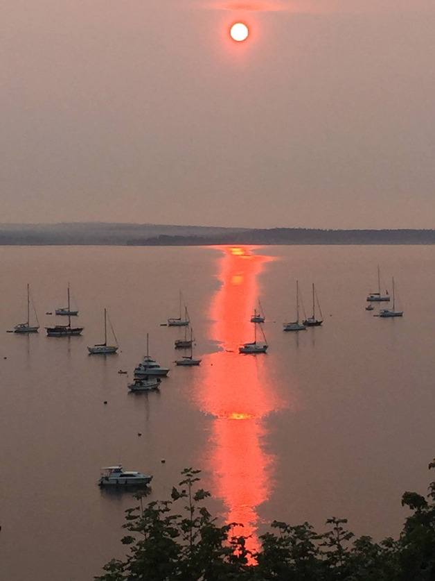 A burning red sun rises over the Cascade Mountains and the Port of South Whidbey Harbor at Langley on Aug. 22. Smoke and haze from wildfires raging in Eastern Washington blew west