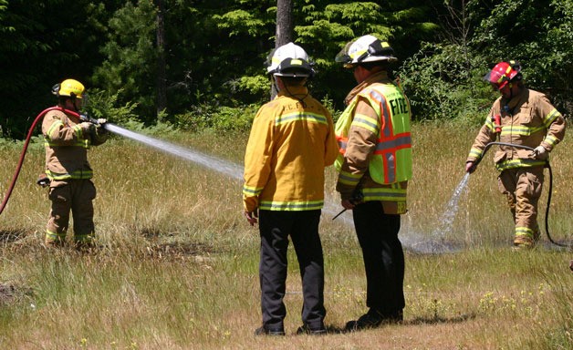 South Whidbey Fire/EMS volunteers work to contain a small brush fire on Cultus Bay Road on Tuesday. The fire began from embers from a burn pile the previous day.