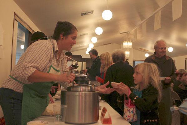 Volunteer Kimberly Shelton (left) hands a young girl a bowl of warm soup at the Good Cheer Empty Bowl Soup Night on Sunday evening.