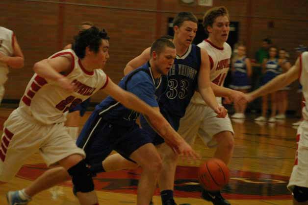 Falcon junior forward Nick French drives to the basket with Wolves Aaron Trumbull and Caleb Valko in pursuit. Below