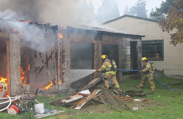 Firefighters from South Whidbey Fire/EMS douse a structure fire in Clinton at a home just off the highway Sunday