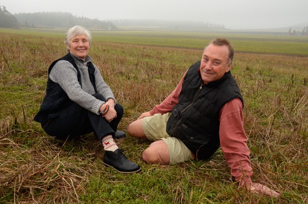 Jan and Ken Pickard pose for a picture before their property in Ebey’s Landing National Historical Reserve. It was one of a handful of properties recently preserved by the Whidbey Camano Land Trust.