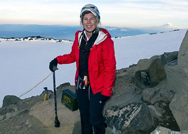 Freeland resident Mary Lou Harris conquers Washington’s highest peak. She signed the summit register in the ammo box behind her. Mount Adams in southwest Washington is in the background.