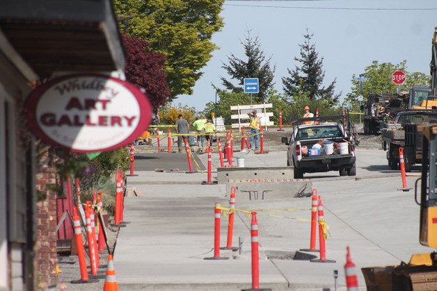 A crew smooths and brushes a section of sidewalk on May 1 in front of Animal Hospital by the Sea and Langley City Hall. Change orders and additional expenses have totaled $227