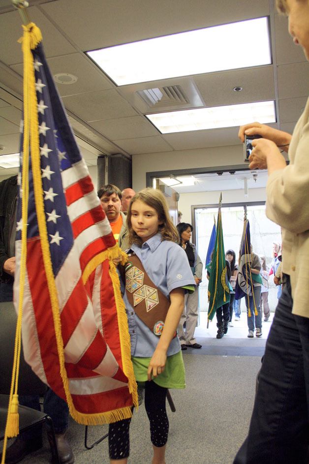 Girl Scout Lexie Smith of Troop 42161 on South Whidbey carries the American flag into a Board of Island County Commissioners’ meeting during a  ceremony honoring Girl Scouts from throughout Whidbey Island last week.