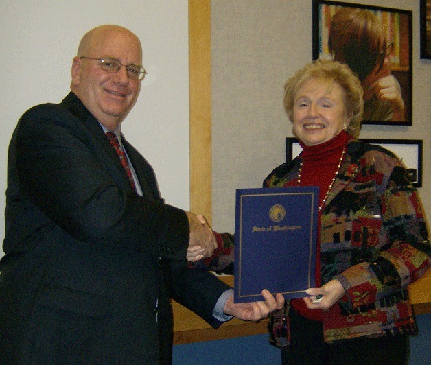 Sno-Isle Libraries Administrative Services Director Arch Fonken gets a congratulatory handshake from Board of Trustees Vice President Jacquelyn DeFazio.