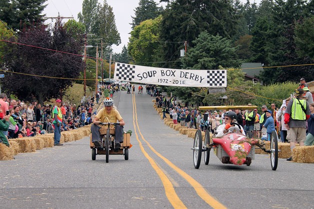 Cary Peterson in her “Produce Basket” (left) laughs after nearly catching Phil Simon (right) during the 2016 Soup Box Derby.