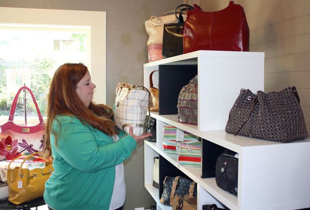 Kimberly Hoctor arranges the designer handbags in her new Coupeville store.