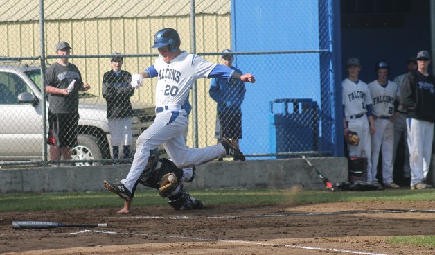 Falcon senior Brent Piehler leaps past Cedarcrest’s catcher to score in the first inning.