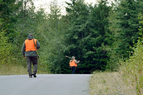 Two deer hunters walk down the paved road left from a previous developer at the Trillium Community Forest near Freeland. Deer hunting is allowed about 42 days  during hunting season