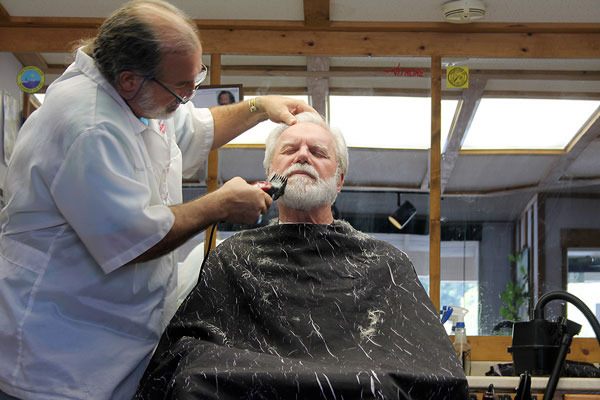 Island Headquarters owner Jeffrey Wood trims Clinton resident Gary Hansen’s beard from Wood’s small “man cave.”