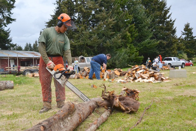 Jorge Flores saws through some tree branches to cut rounds for the Hearts & Hammers Woodchucks — volunteers who chop firewood for residents in need.