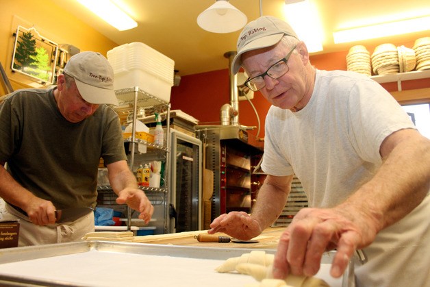 Larry Lowary places croissants onto a baking sheet while Gerry Betz rolls together pain au chocolat in their Clinton home bakery