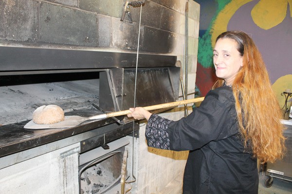 Kelly Baugh removes a loaf of bread from her brick wood-fire oven.