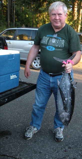 Chuck Prochaska holds up one of the tuna fishes bought to feed the Grange community.