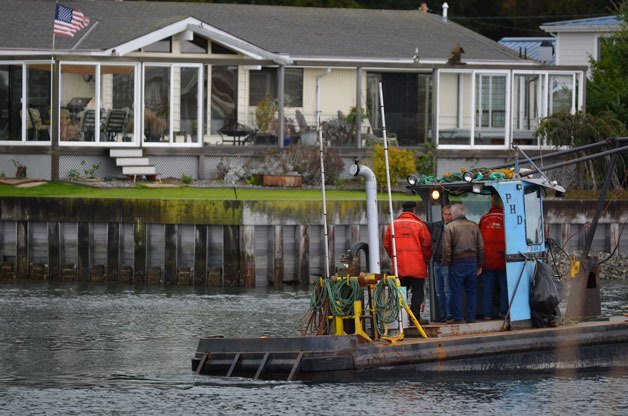 Workers survey a bulkhead on a waterfront home at Lagoon Point last week after dredging work at the private marina was completed. It was a complicated project that spanned about six years.