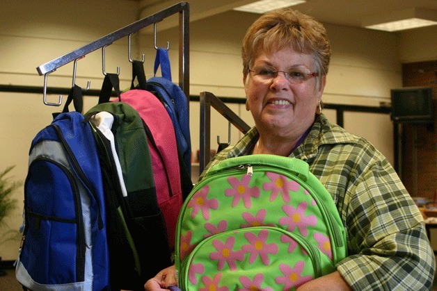 Roy Jacobson / The Record Volunteer Mary Green of Langley straightens a rack of backpacks Thursday at the Back to School Project “store” in a classroom at the former South Whidbey Primary School.