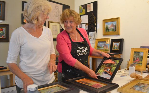 Faye Castle and Phyllis Ray make frame in preparation for their art pieces in the Whidbey Island Open Studio Tour this weekend.