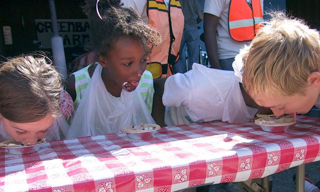 Pie-eating contestants race to finish their mini-pies during Saturday’s Loganberry Festival at Greenbank Farm. Below