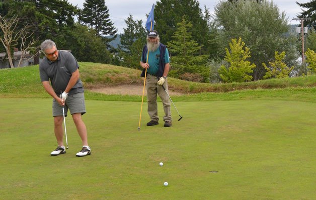 Evert Olkonen and Ken Porter seizes the opportunity for a hole at the newly opened Holmes Harbor Golf Course Thursday morning. The course was packed with all but two of the 22 carts on the greens.