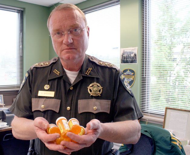 Sheriff Mark Brown holds some of the returned  prescription medication bottles. More than a half-ton of pills were turned in during the last two drug  disposal events on Whidbey Island.