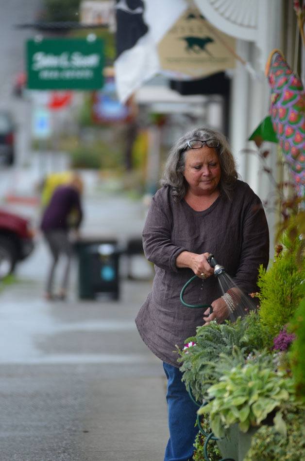 Michele LaRue waters the plants in front of her First Street store.  Langley city officials are planning a series of economic forums