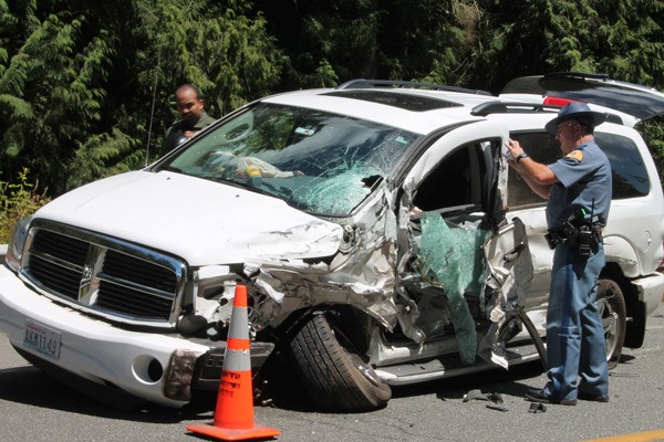 A Washington State Patrol trooper photographs one of two vehicles involved in a collision on Highway 525 today. Three people were sent to the hospital