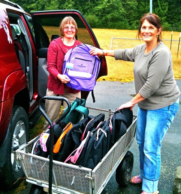 Volunteers Susan Haskins and Joanie Smith unload backpacks donated by Boeing. Donations of items and time will help the Back to School project give supplies to students in need.