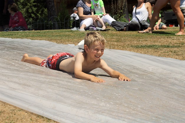 A boy enthusiastically enjoys the water slide set up by South Whidbey Parks and Recreation at the “Beat the Heat Waterworks” event on July 23 at Community Park. South Whidbey Parks and Recreation utilized a warm day to sponsor the cooling event. Laura Zulaski and her son Poseidon Frickberg were unaware of the fun that was being had on the hill and decided to check it out. “We were just coming to the park and didn’t know what was going on
