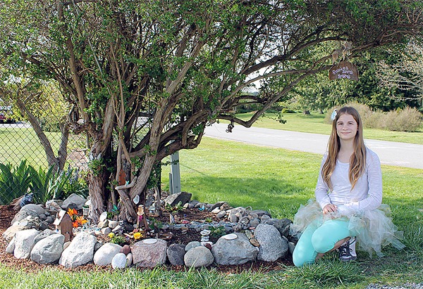 Emily Fiedler sits next to the fairy garden she and her sister Hayley made after building several fairy houses and dolls at Meerkerk over four years.