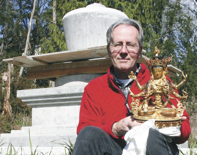 Chuck Pettis with the gold-painted Buddha statue which will be sealed in Earth Sanctuary’s new Victory Stupa behind him.