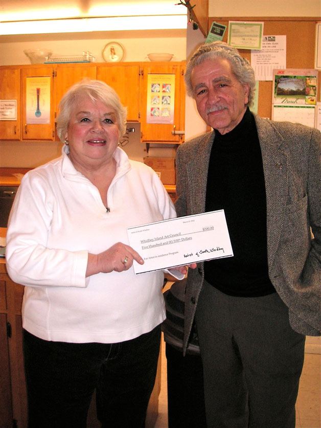 Barbara Enberg presents Whidbey Island Arts Council president Frank Rose with a check for the artist-in-residence program trying to find a foothold at the schools.