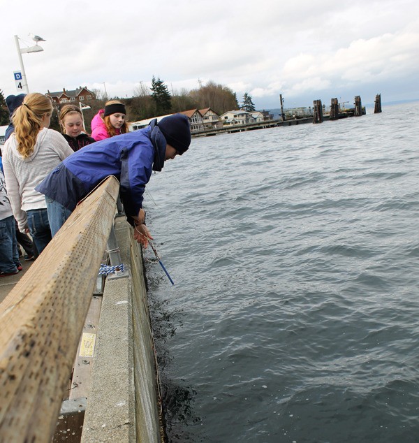 Langley Middle School seventh graders Mallory Dye and Mattason Straub look on as Ben Roughsedge releases the Van Dorn bottle into the water at South Whidbey Harbor during the marina-based learning day