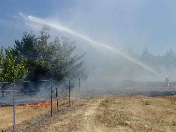 A firefighter hoses down a brush fire off Double Bluff Road today. Officials say it was the largest since the 1990s.