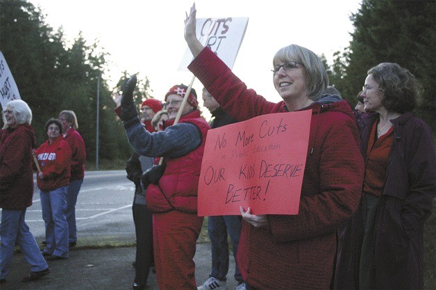 Becky Ward waves to passing traffic on the corner of Maxwelton Road and Highway 525 on Monday afternoon. She was just one of 18 teachers from the union South Whidbey Education Association who rallied against proposed budget cuts as state legislators meet in a special session to reduce its  deficit.