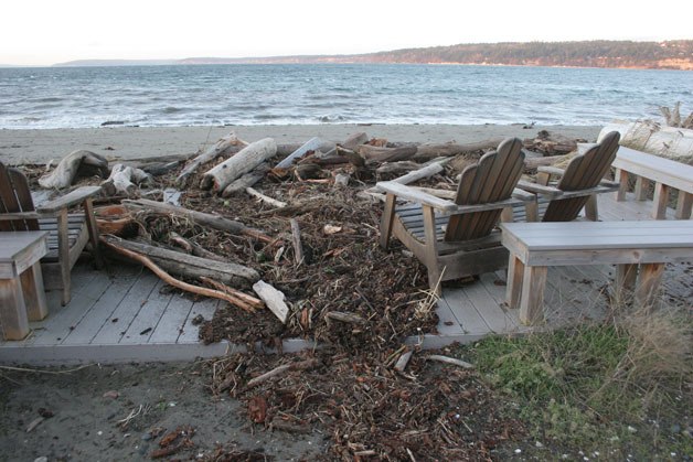Logs and other debris pushed ashore by high wind and wave action Thursday morning spill across a deck in a front yard near Sandy Point.