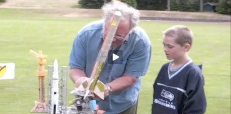 Leonard J. Good (left) demonstrates the finer points of backyard rocket-making to a young observer.