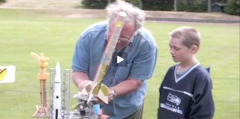 Leonard J. Good (left) demonstrates the finer points of backyard rocket-making to a young observer.