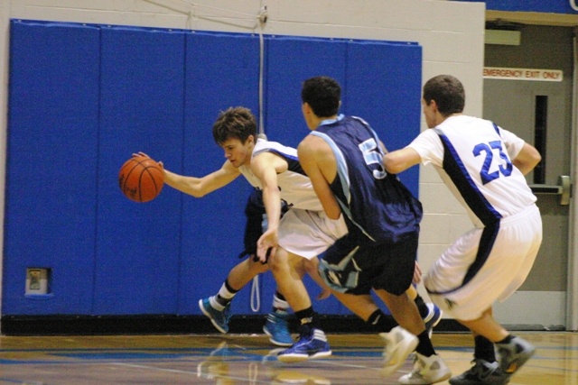 Taylor Simmons scrambles to dribble a loose ball against Turk junior forward Steven Branham as Falcon sophomore Nick French sets a back screen.