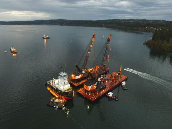 Two cranes on barges prepare to help a new tugboat to deep water Wednesday in Holmes Harbor. This shot was from a drone piloted by David Moore.