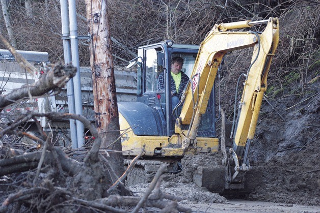 Dale Strickland works to remove slide debris in Whidbey Shores on Monday: “If we get another gully washer