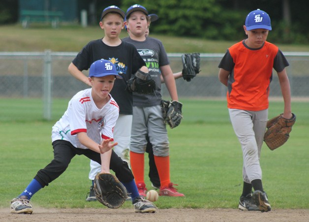 Josh Sterba tracks a grounder during practice for the South Whidbey Little League 9/10-year-old All-Stars at Community Park on June 23. Behind him are Tyler Thrasher and Andrew Hilton. To the right is Nick Black. Their District 11 games are in Sedro-Woolley.