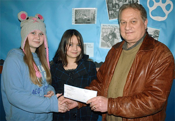Langley Middle School students Leena and Lakota Clarkson receive a $400 check from Nichols Brothers Boat Builders CEO Matt Nichols in response to a presentation the students made at the Freeland business on behalf of the nonprofit Ryan’s House for Youth.