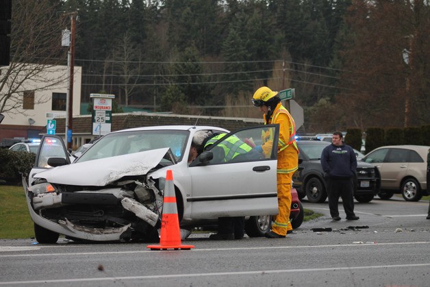 Emergency responders from South Whidbey Fire/EMS and Whidbey General Hospital EMS speak to Eric Ray of Greenbank after he was in a car crash on Highway 525 near Harbor Avenue in Freeland on Friday afternoon. He was able to walk away from the car before being taken to his nearby doctor's office.