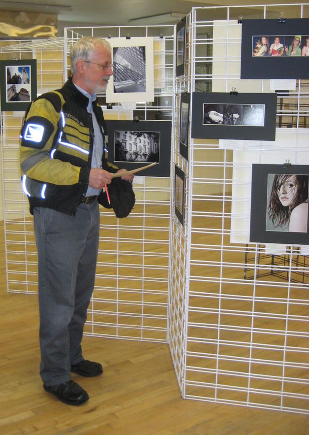 Photography judge John Olsen takes in the photos at a recent Showcase of the Arts show and contest in Coupeville.